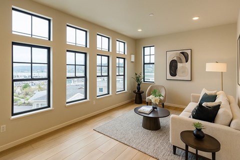 A living room with a white couch, a coffee table, and a large window overlooking a cityscape.