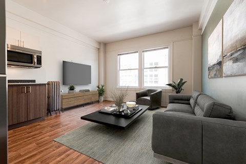 A modern living room with a grey couch, a coffee table, and a large window.