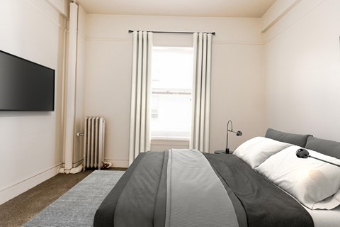 A bedroom with a large bed and a flat screen TV mounted on the wall.
