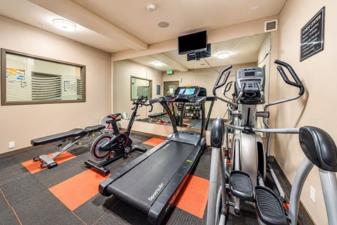 A gym with treadmills, exercise bikes, and a television.