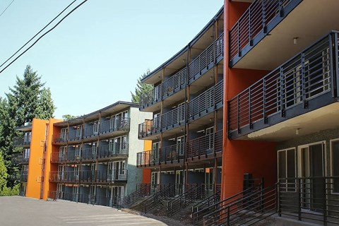 A modern apartment building with orange and grey balconies.