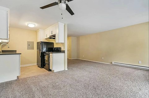 A kitchen with a black fridge and stove top oven.