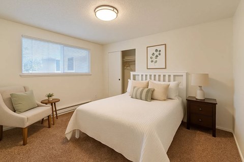 A bedroom with a large bed and a chair.