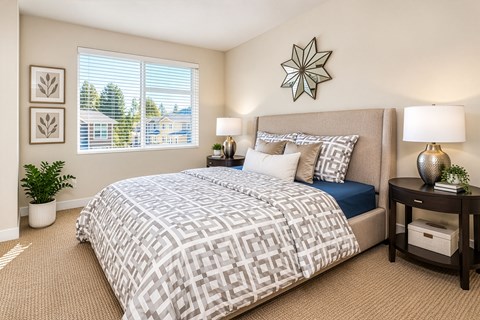 A bedroom with a large bed and a window with blinds.