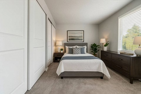 A bedroom with a bed, nightstands, and a window with blinds.