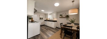 A kitchen with white cabinets and a wooden table.