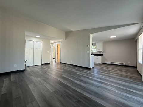 A spacious room with wooden flooring and white walls.