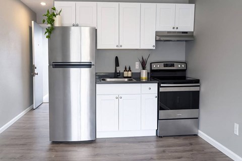 A modern kitchen with a stainless steel refrigerator and white cabinets.