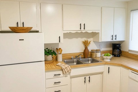 A kitchen with white cabinets and a wooden countertop.