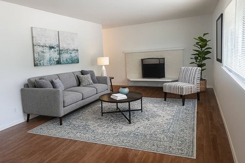A living room with a grey couch, a coffee table, and a painting on the wall.
