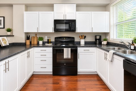A black stove top oven sits in a kitchen with white cabinets.