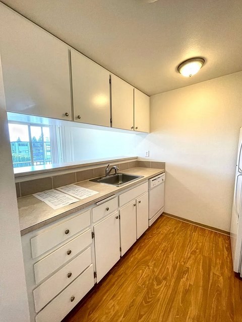 A kitchen with white cabinets and a wooden floor.
