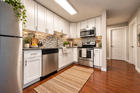 A kitchen with white cabinets and a stone backsplash.