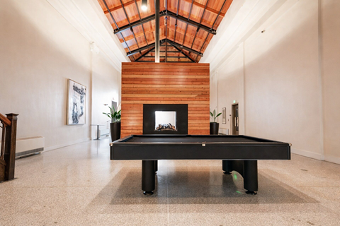 A pool table in a room with a fireplace and a skylight.