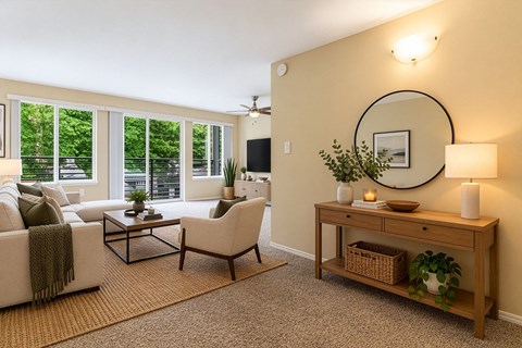 A living room with a white couch, a coffee table, a chair, a TV, and a plant.