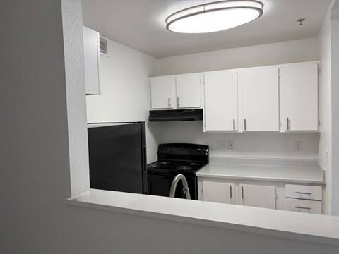 A black dishwasher is in a white kitchen.