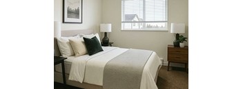 A bedroom with a large bed and two lamps.