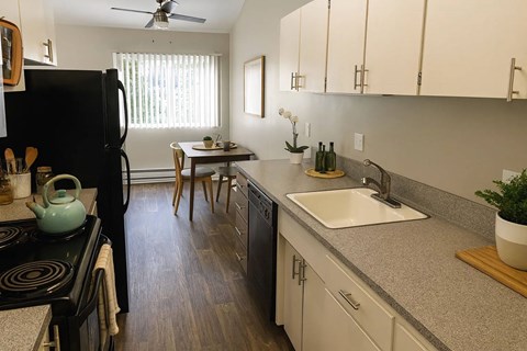 A kitchen with a black refrigerator and wooden floors.