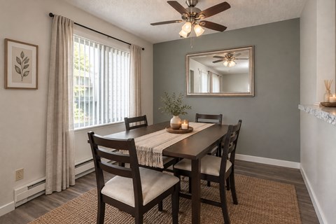 A dining room with a table set for two and a ceiling fan.