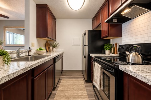 A kitchen with dark wood cabinets and a black refrigerator.