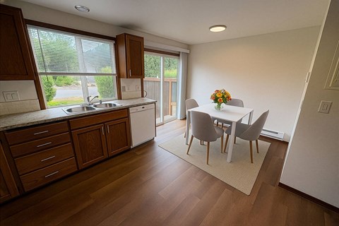 A kitchen with wooden cabinets and a dining table with chairs.