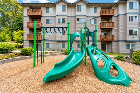 A green playground slide in front of a building.