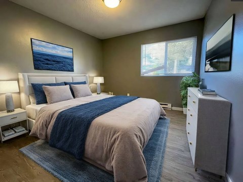 A bedroom with a large bed and a painting on the wall.