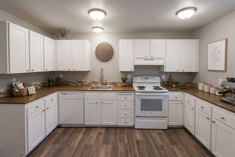 A kitchen with white cabinets and a wooden floor.