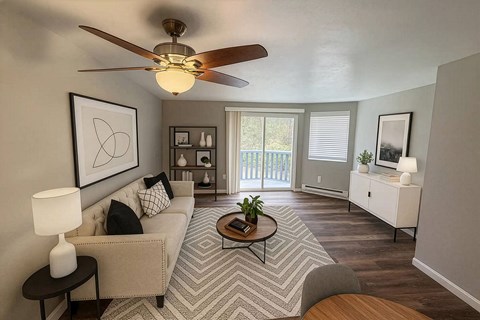 A living room with a beige couch, a coffee table, and a ceiling fan.