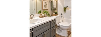 A white toilet sits in a bathroom with a sink and a mirror.