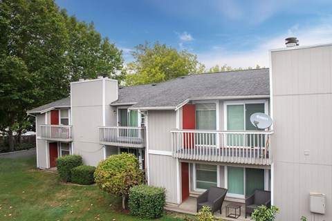 A small white house with a red door and a balcony.