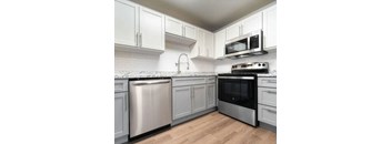 A kitchen with white cabinets and a stainless steel refrigerator.