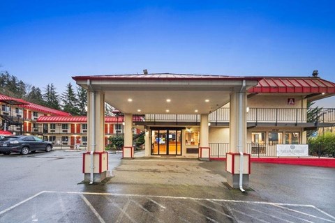 A parking lot in front of a building with a red roof and white pillars.
