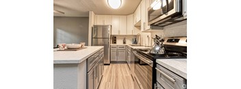 A modern kitchen with stainless steel appliances and wooden floors.