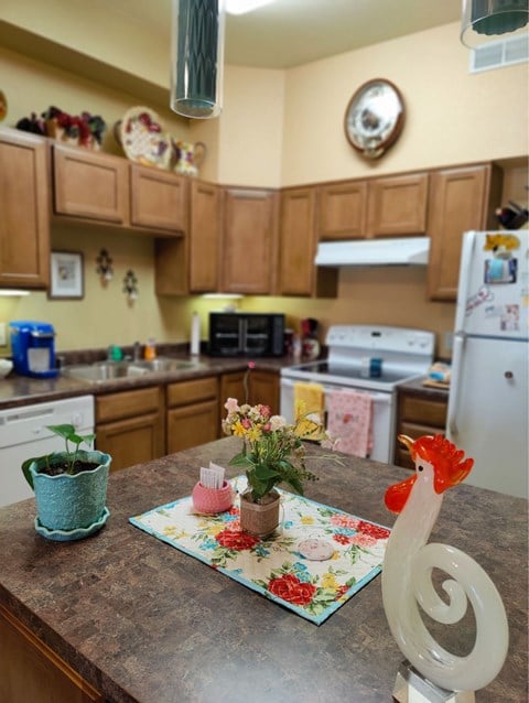 A kitchen with a table and a rooster statue on it.