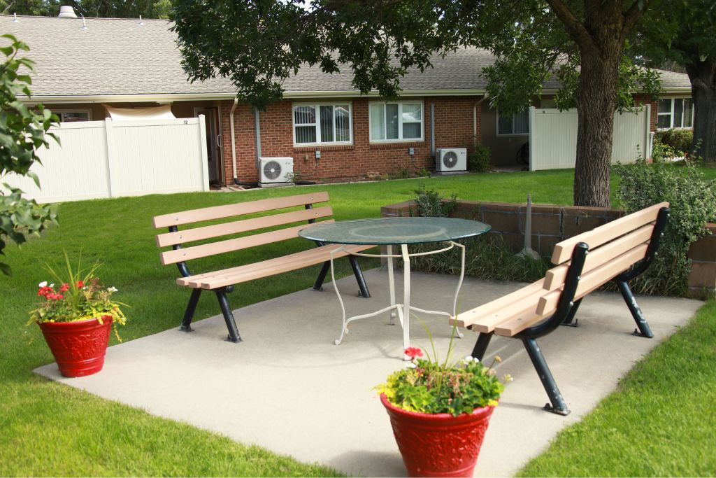 A backyard with a table, chairs and potted plants.