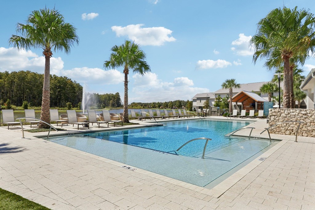 A swimming pool surrounded by palm trees and lounge chairs.
