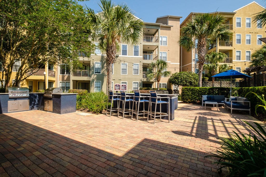a patio with tables and chairs in front of an apartment building