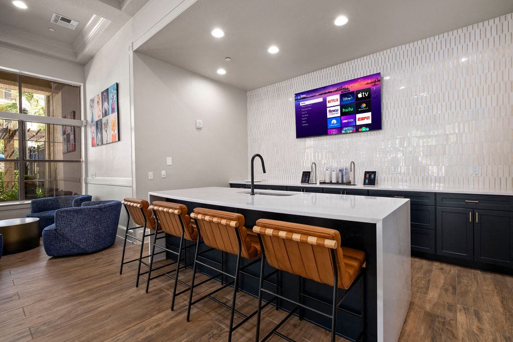 a kitchen with a counter and chairs and a tv on the wall