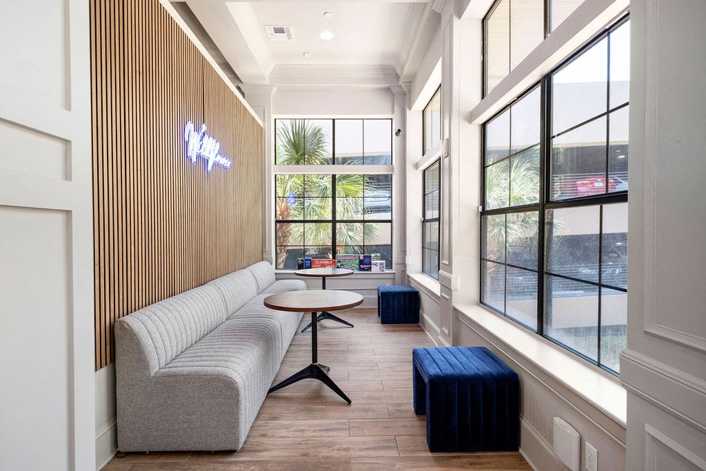 a seating area with a couch and table in a room with large windows