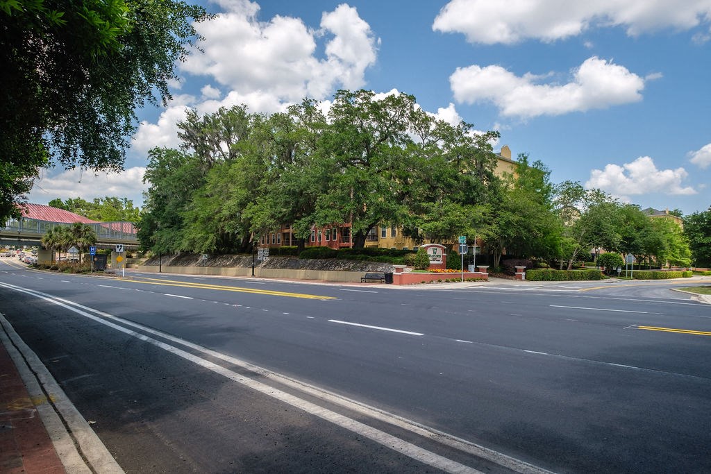 an empty street with trees and a building in the background