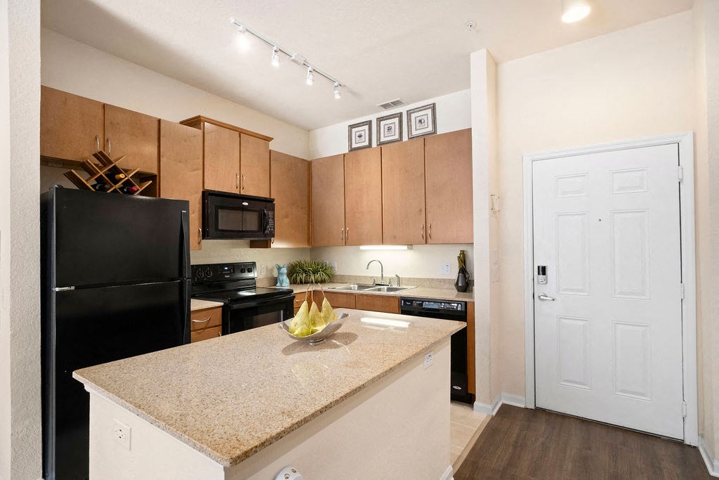 a kitchen with a granite counter top and a black refrigerator