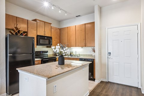 A kitchen with a black refrigerator and white cabinets.