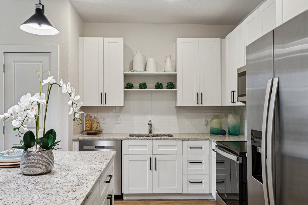 A kitchen with white cabinets and a marble countertop.