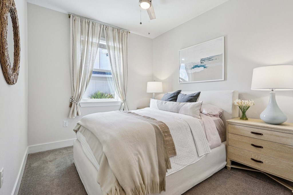 A bedroom with a large bed, a window with curtains, and a painting on the wall.
