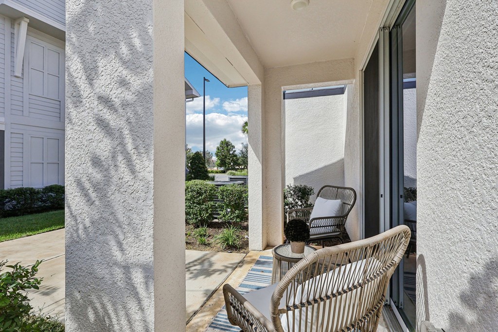 A patio with a chair and table is seen through a sliding glass door.