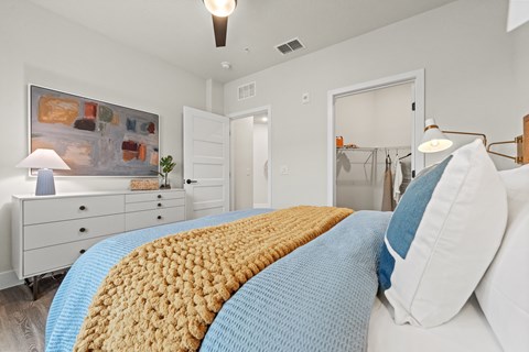 A bedroom with a bed covered in a yellow and blue blanket.