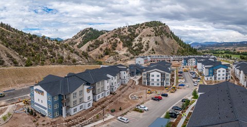 A construction site with a large building under construction in the foreground and a mountain in the background.
