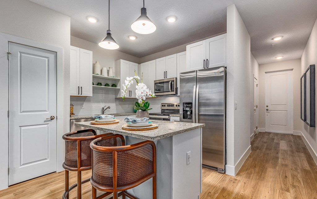 a kitchen with stainless steel appliances and a island with three chairs