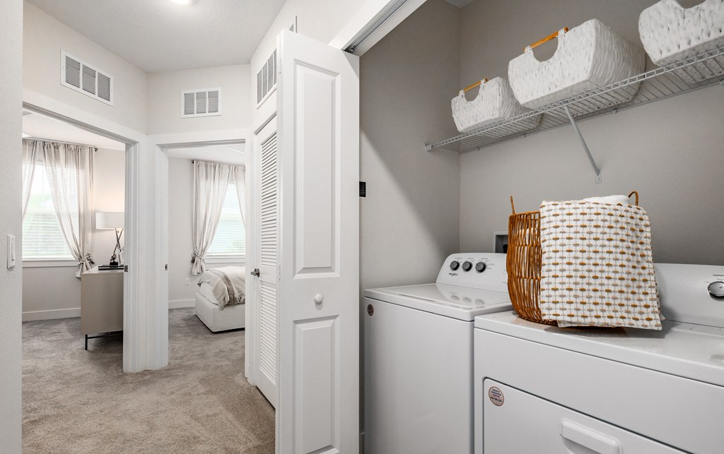 a washer and dryer in a laundry room with a door to a bedroom